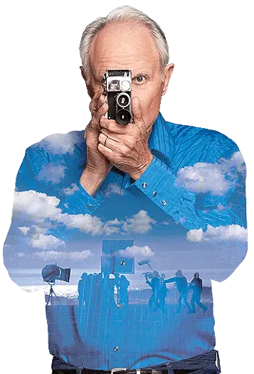 A man holding a camera with clouds in the background.