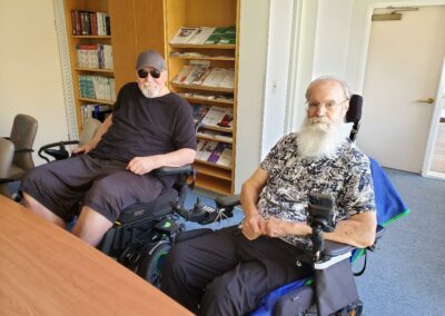 Two men in wheelchairs sitting at a table.