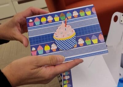 A person holding a card with a cupcake on it.