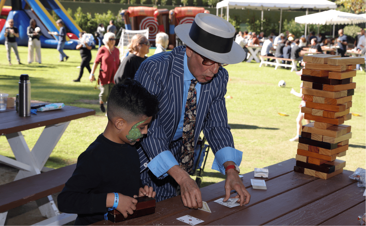 A man shows a trick using a deck of playing cards to a boy