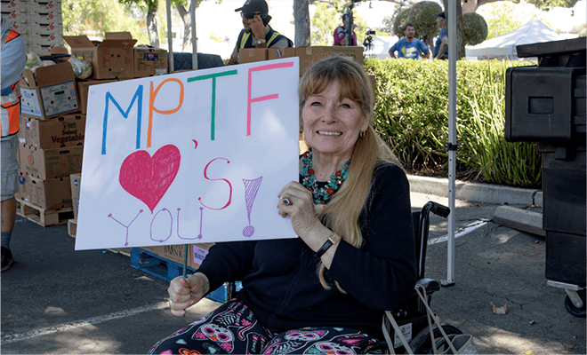 A woman in a wheelchair holding a sign.