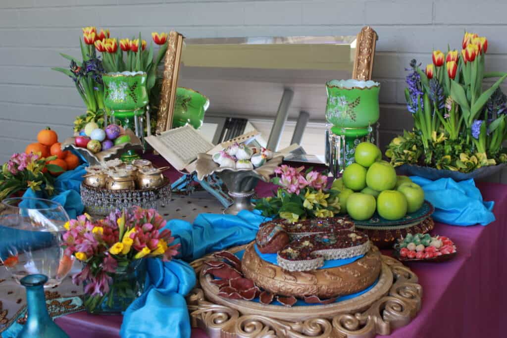 Colorful banquet table with an assortment of fruits, cakes, flowers, and decorative objects.